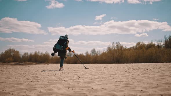 Unrecognizable Person Scanning the Sand with Metal Detector To Find Precious Metals.