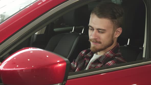 Handsome Young Man Sitting Comfortably in His New Car Smiling To the Camera