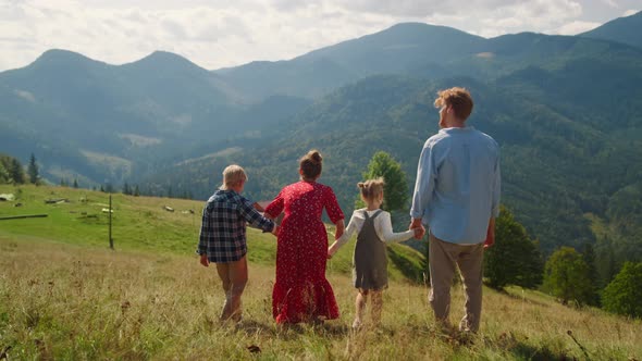 Family Walking Down Green Mountain Hill Back View