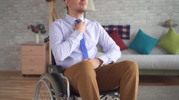 Disabled Man in a Wheelchair Dresses in Front of a Mirror