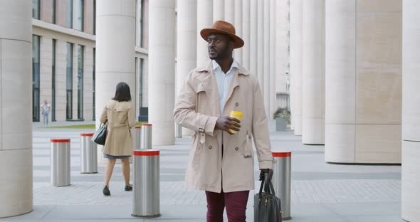 Slider Shot of Handsome African American Entrepreneur Walking with Coffee Cup Outdoors