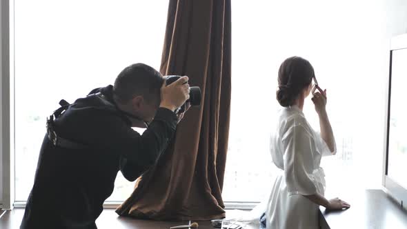 The Photographer Takes a Picture of a Beautiful Bride In a Wedding Dress By the Window
