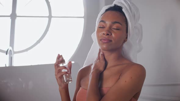 Black Woman Spreading Oil on Her Skin After Bath with Her Hair Wrapped in Towel