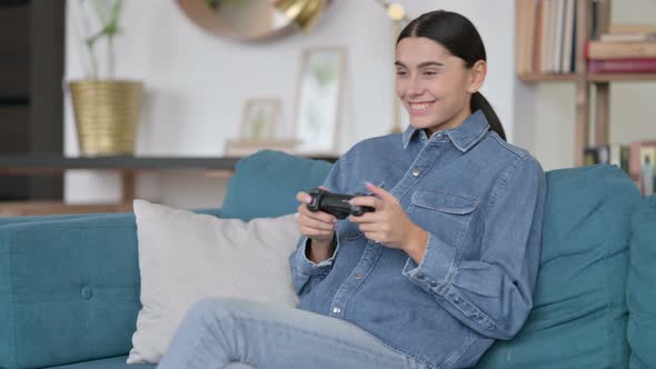 Attractive Latin Woman Playing Video Game on Sofa