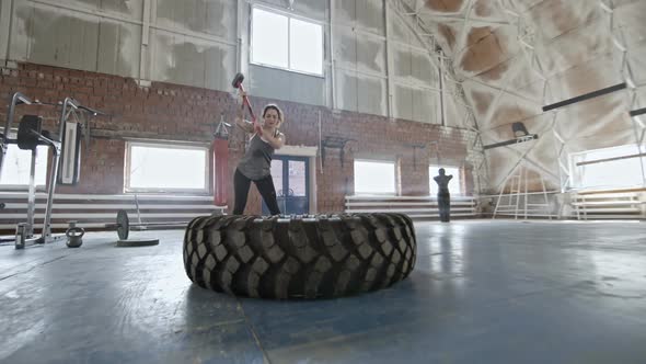 Woman Doing Sledgehammer Exercise with Tire