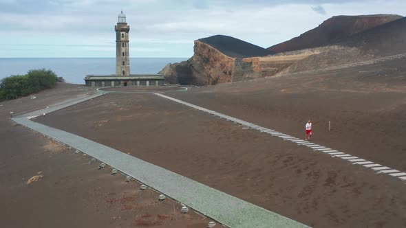 Sportsman Running on Path with with Volcano Interpretation Center of Capelinhos