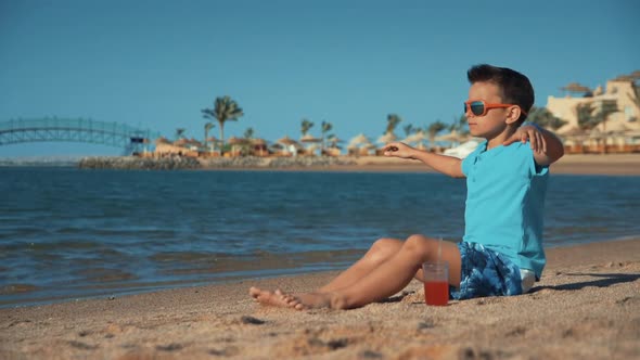 Attractive Man Sitting with Glass of Juice on Sand Coastline in Summer Vacation.