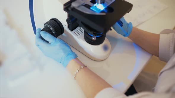 a Doctor in a Modern Clinic Works Behind a Fluorescent Led Microscope