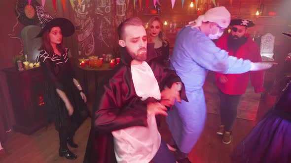 Young Man in Evil Vampire Costume Dancing in the Middle of a Group of Friends Celebrating Halloween