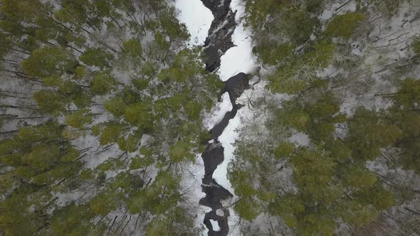 Drone flying above snowy river in winter