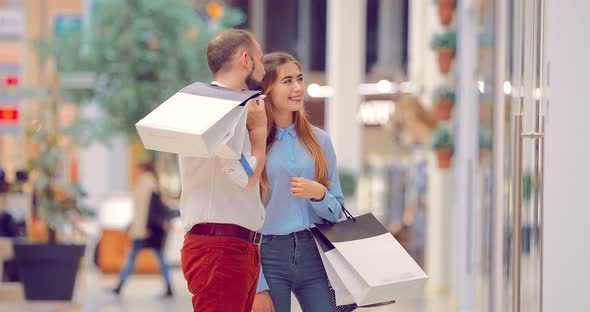 Young Beautiful Couple in the Mall is Standing Near the Shop Window