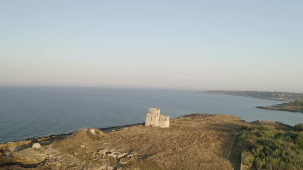 Aerial shot of coastline with a small castle on the beach