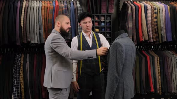 Slow motion of handsome man choosing a suit design with tailor in atelier