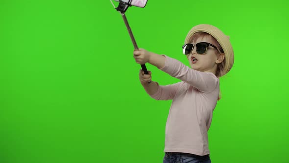 Girl Child Makes Selfie, Blogging on Mobile Phone Using Selfie Stick. Chroma Key