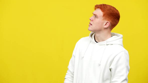 Side View of Surprised Redhead Man Standing on the Right at Yellow Background Looking Away Grimacing