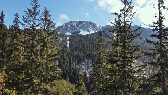 Aerial drone view of the spring Carpathians, Romania. Rocky peaks and valleys partly covered with sn