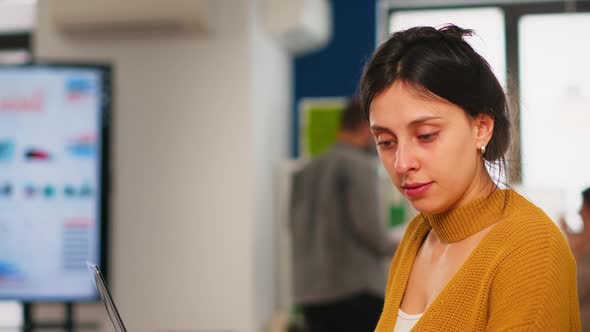 Young Woman Working at Laptop Sitting at Desk in Busy Financial Startup Company