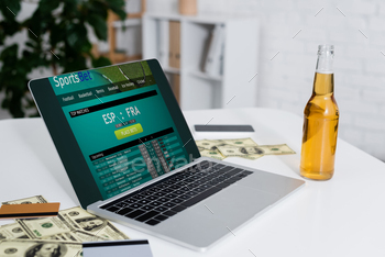 dollar banknotes and beer near laptop with sportsbet