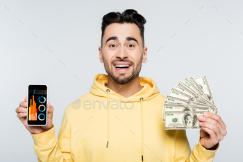 happy bookmaker with dollars showing smartphone with analytics isolated on grey