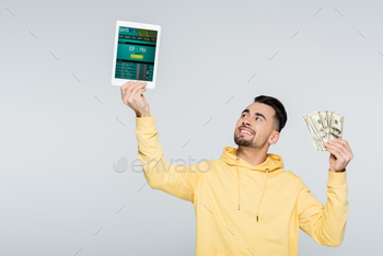 aker holding dollars and digital tablet with