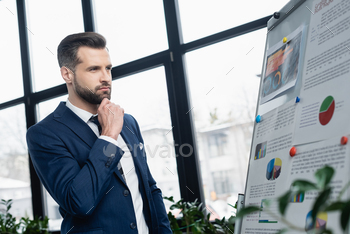 thoughtful economist looking at flip chart with graphs in office