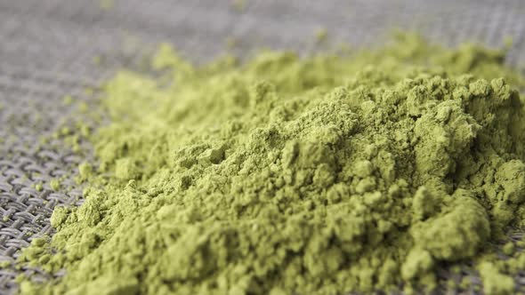 Pure Japanese matcha tea powder falls into a heap in slow motion