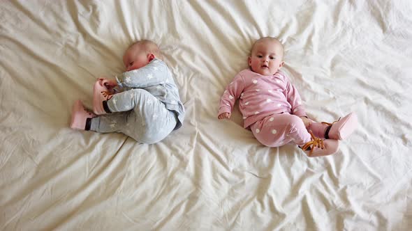 Two girls sisters lie on the bed. Two baby twins on the bed