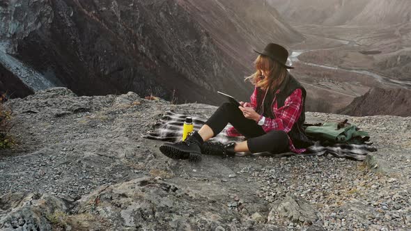 Woman Hiker Use Digital Tablet at Mountain Peak Cliff