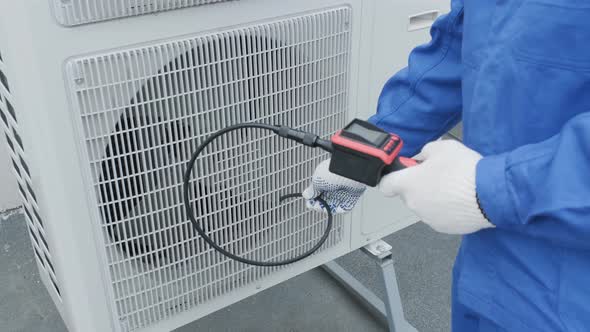 The technician uses a digital camera to check the clogging of the heat exchanger