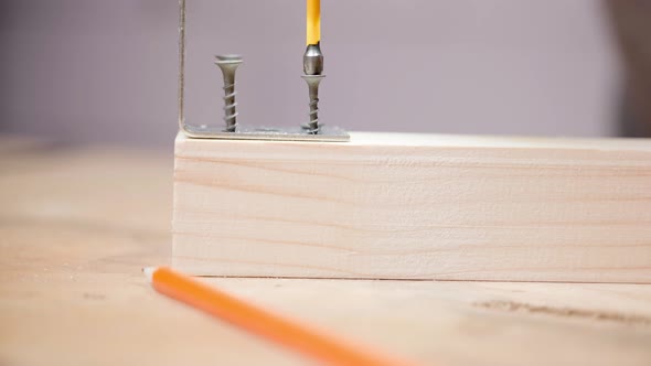 A Crosshead Screwdriver Screws a Selftapping Screw Into a Wooden Bar for Attaching a Metal Corner