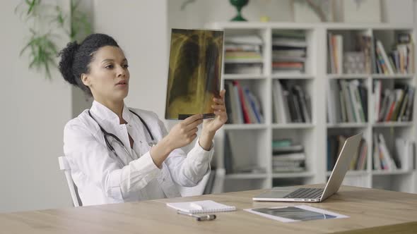 A Young Female Doctor Conducts an Online Video Consultation with Patient and Examining Snapshot of