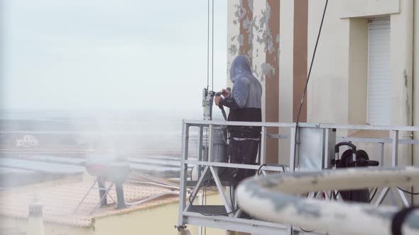 A Man Uses a Highpressure Machine to Disinfect the Walls of a Multistorey Building for Subsequent
