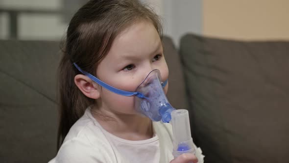 Little Girl Does Inhalation with a Mask on Her Face at Home