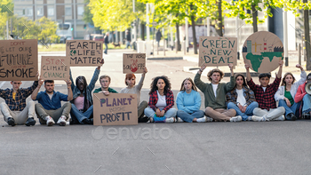 A group of activists gather in an urban setting, holding signs that call for action against climate change. Their placards bear powerful messages.