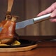 A Man's Hand Cuts a Large Piece of Meat From a Pork Knuckle with a Knife - VideoHive Item for Sale