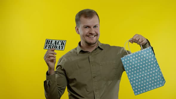 Man Showing Black Friday Inscription From Shopping Bag, Smiling, Rejoicing Discount, Low Prices