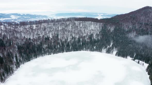 Frozen volcanic crater Lake Saint Ann, Romania. Cinematic aerial drone footage