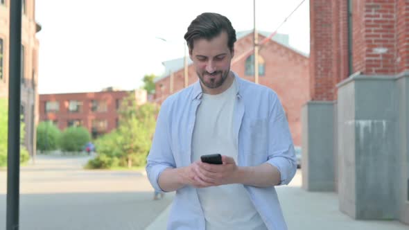 Man Using Smartphone While Walking on Street