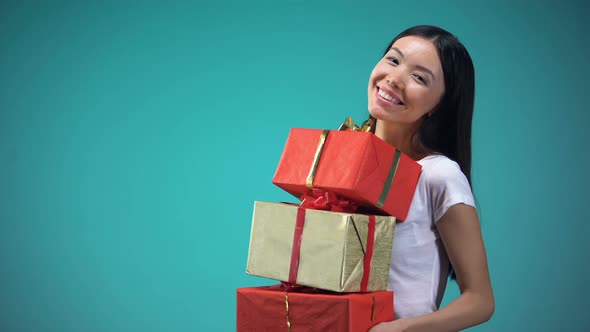 Smiling Girl Holding Many Giftboxes, Fest Presents, Standing on Blue Background