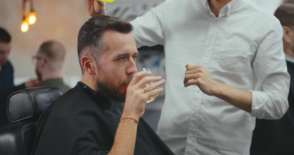 Hipster Man Drinking Whiskey Having Hair Combed By Hairdresser