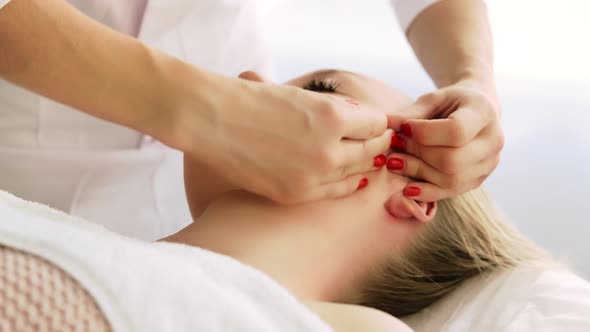 Beautician cosmetologist makes lifting face massage, pinch and roll technique