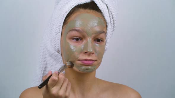 Teenager Wearing Bath Towels Applying Clay Mask on Face at Home Spa