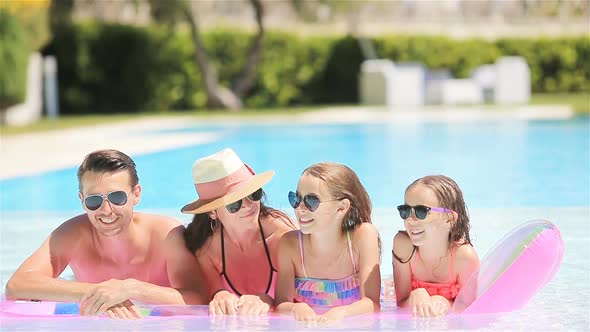 Happy Family of Four in Outdoors Swimming Pool