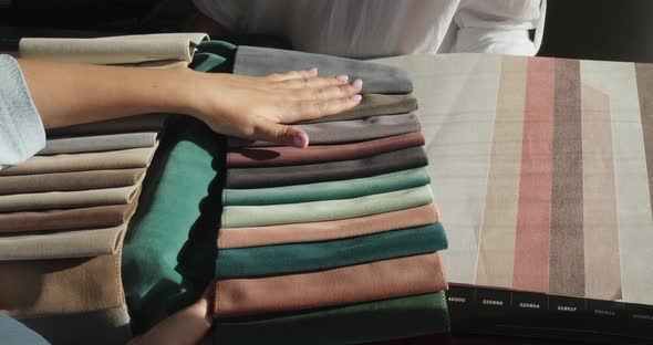 A Woman's Hand Strokes the Fabric Samples That the Designer Holds Next to the Wallpaper Samples