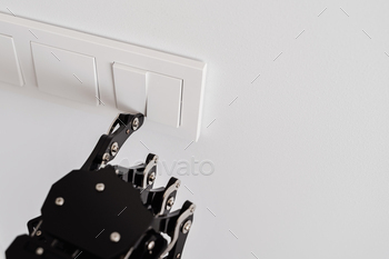 Real robot's hand pressing button on a light switch. Concept of robotic process automation