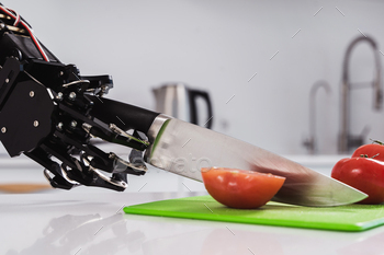 Real robot's hand cutting fresh tomatoes with sharp knife. Concept of robotic process automation