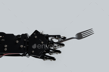 Real robot's hand with fork. Concept of AI development and robotic process automation