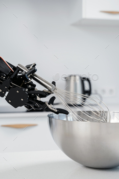 Real robot hand and stainless steel whisk. Concept of robotic process automation.