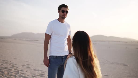 Young Stylish Couple in Desert Wearing Both Jeans Sunglasses and White T Shirts Long Haired Brunette