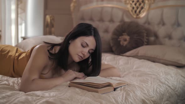 Beautiful Caucasian Woman Lying on the Bed and Reading a Book